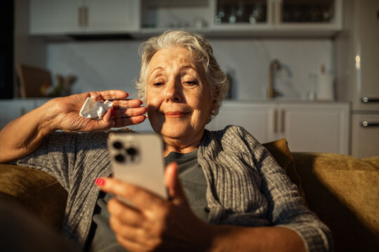 Senior woman using smartphone and tissue on couch