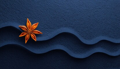 A single star anise rests on a dark blue surface with sculpted waves