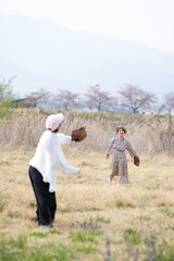Naklejka premium A woman in a white shirt and black pants is playing baseball with a man in a brown hat