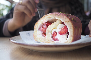 Sweet dessert roll with strawberries and cream on a plate