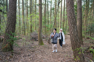 Two women walking in a forest. One of them is holding a baby