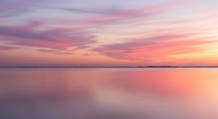 Obraz premium Serene pastel sky reflects on calm water at dawn, painting a tranquil, dreamlike landscape.