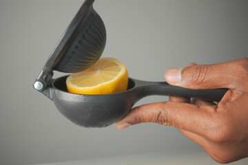 Juicing lemon with a hand-held citrus press in the kitchen
