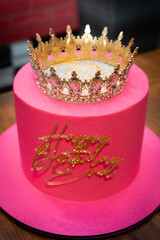 The cake is bright pink with a crown on top and the words: Happy Birthday Eva!