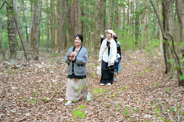 A woman is walking in a forest with a baby in her arms. The baby is wearing a hat