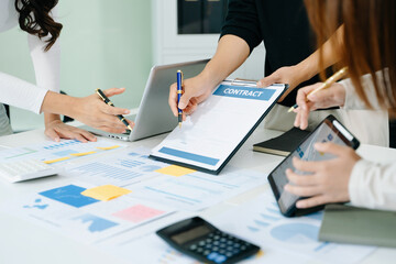 Businessman hand using laptop and tablet with social network diagram and two colleagues discussing...