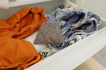 Lavender pouch resting on colorful fabrics in a drawer