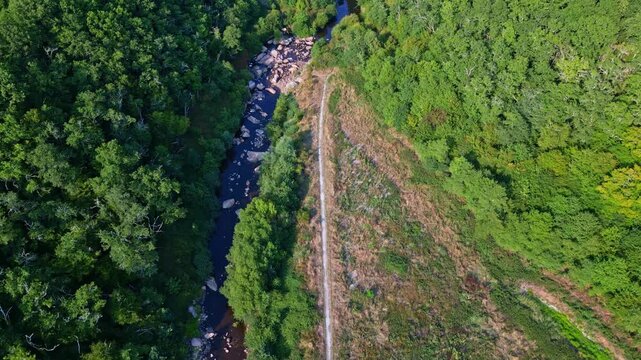 A stunning aerial shot of the Gu&eacute; Giraud, with a winding river lined by lush forest and a scenic path running alongside it. Near Saint-Junien