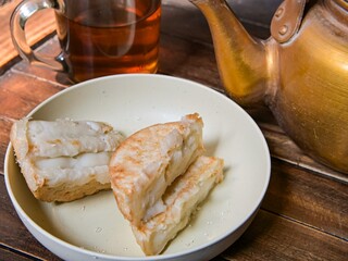 Indonesian Pancong cake snacks on a plate accompanied by warm tea on the dining table.