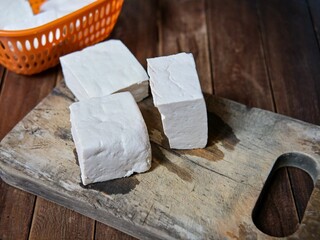 Fresh raw tofu in a plastic basket and on a cutting board. Fresh tofu ready to cook.