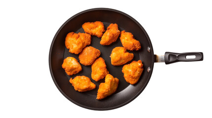 A top down view of golden brown chicken nuggets cooking in a nonstick frying pan on a black background