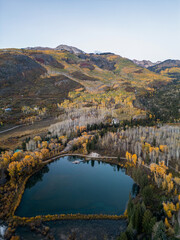 Scenic aerial view of a mountain lake surrounded by colorful autumn aspen trees and forest during...