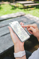 Businesswoman using smartphone with monthly calendar to plan 2026 activities. Scheduling and...