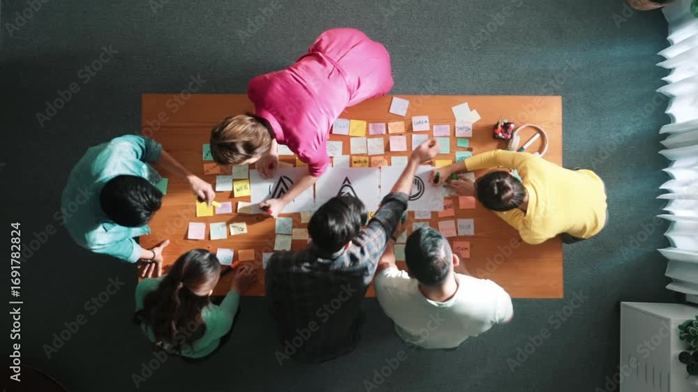 Poster top down aerial view of skilled designer hold logo while discuss with team. aerial business group wo