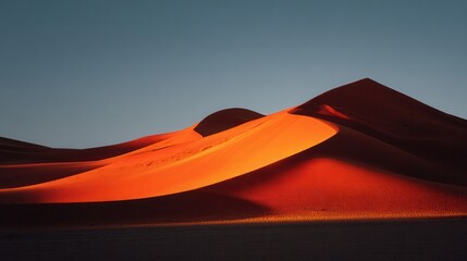 Dramatic desert sand dunes illuminated by warm sunset light