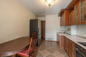cozy kitchen with wood cabinets, a large fridge, and a round dining table with chairs.  Tiled floor and warm lighting give it a homey feel
