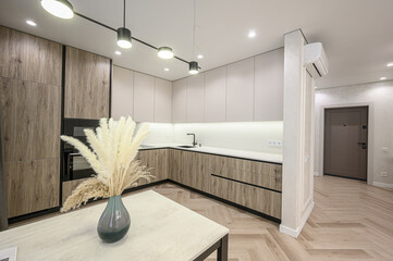modern kitchen interior featuring sleek cabinets, a dining table with vase, and herringbone wood...