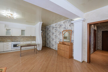room featuring a kitchen area with white cabinets, a wooden table, and a dresser with a mirror, under warm lighting