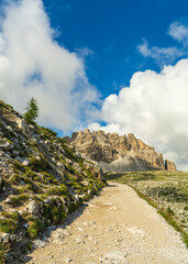 Famous hiking trail winding around iconic Drei Zinnen peaks in Dolomites, Italy. Breathtaking alpine scenery with dramatic mountains, rocky terrain, clear skies. Perfect for travel themes