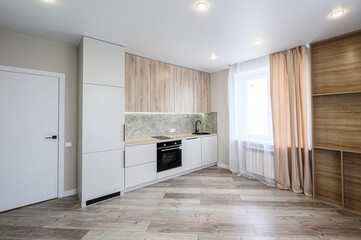 modern kitchen with white cabinets, wood accents, and a large window. The room is bright and clean