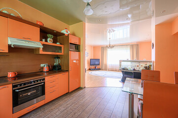 Bright, open interior with orange kitchen cabinets and a view into a living area featuring an aquarium