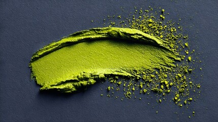 Vibrant chartreuse green makeup smudge with fine particles on a dark gray textured background
