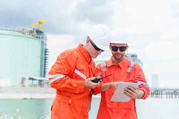 Engineers inspecting oil refinery and gas pipeline system with tablet