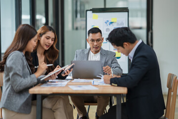 Group of Asian businesspeople sits down for a business investment planning meeting.