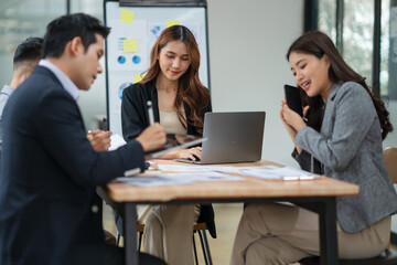 Group of Asian businesspeople sits down for a business investment planning meeting.
