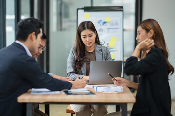 Group of Asian businesspeople sits down for a business investment planning meeting.
