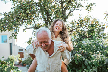 Grandfather playing with granddaughter in the garden.