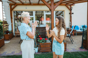 Grandmother and granddaughter playing clapping game.