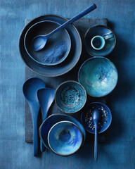 Flat lay of blue bowls and utensils arranged on soft blue background.
