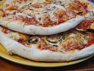 Freshly baked pizzas with melted cheese and toppings served on a rustic plate at an Italian...