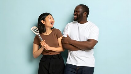 Asian Woman and African American Man Holding Cooking Utensils with Happy Expression in Studio
