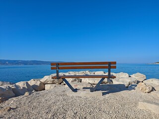 Peaceful bench overlooking calm waters at a coastal location on a bright, sunny day