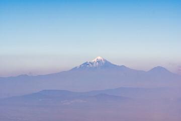 Fototapeta premium A mountain range with a blue sky in the background. The mountains are covered in snow and the sky is clear. Iztacihuatl popocatepetl volcano mexico,