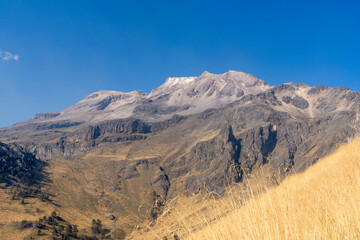 A mountain range with a clear blue sky in the background. The mountains are covered in snow and the...