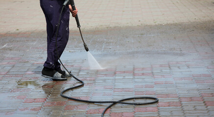 A man is cleaning a sidewalk with a pressure washer