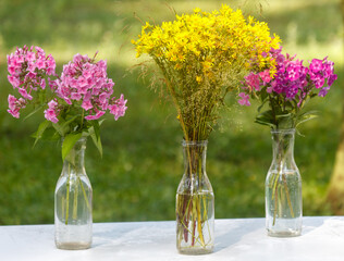 Three vases of flowers are on a table