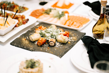 Delicious gourmet meal featuring sushi, cured meats, and fresh vegetables at a banquet table