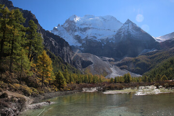 Fototapeta premium Majestic snow peaks tower over serene alpine rivers and lakes Yading Nature Reserve, Sichuan, China