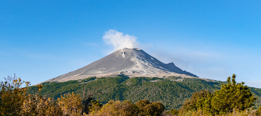 A mountain with a cloud of smoke rising from it. popocatepetl volcano mexico,