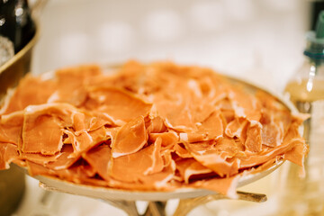 Freshly sliced cured ham served on a metal platter at a gourmet food event