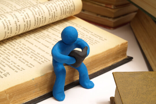 A plasticine man sits and reads a book