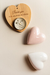 Flat lay composition with a wooden heart box, tea light candle, and ceramic hearts on light...