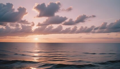 Obraz premium Sunset over the ocean with soft clouds