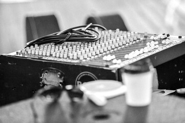 A sound mixing desk with a cable coiled on top  - monochrome - horizontal