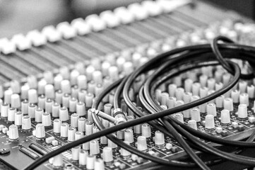 A sound mixing desk with a cable coiled on top  - monochrome - horizontal