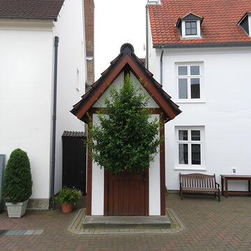 Little cort in house with treen in center. Houses are white. Bruges, Belgium